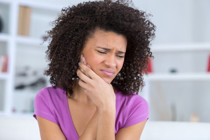 Woman experiencing jaw pain from TMJ disorder