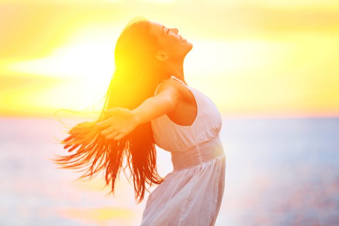 Woman smiling in sunlight with a bright healthy smile